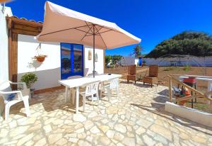 eine Terrasse mit einem weißen Tisch und einem Sonnenschirm in der Unterkunft Villa Nica in Granitola
