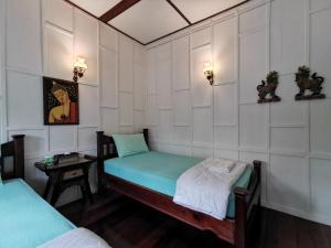 a small room with two beds and a table at TAVEE Guesthouse in Bangkok