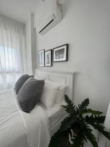 a bedroom with a bed with white sheets and a plant at The Penthouse TROIKA KOTA BHARU in Kota Bharu