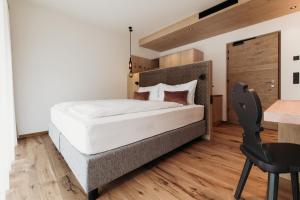 a bedroom with a bed and a desk and a chair at Weingut & Genusshotel Spitalerhof Superior in Chiusa