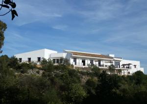 una casa blanca en una colina con árboles en Centro de Naturaleza Cañada Verde "El Parque de Naturaleza con mas experiencias de Andalucía"", en Hornachuelos