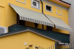 un edificio giallo con tenda da sole verde e bianca di A casa di Anna, elegant flat in Cremona a Cremona