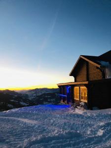 a log cabin in the snow with the sun setting at Mate's Shack in Khulo