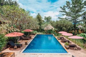 una piscina con sombrillas y sillas en Villa Khao Phaengma, en Wang Nam Khiao