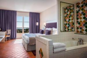 - une chambre d'hôtel avec un lit et une baignoire dans l'établissement Le Fregate Provence, à Bandol
