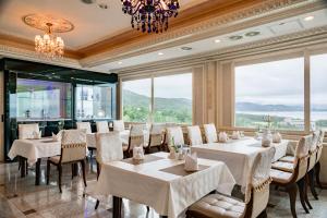 a restaurant with white tables and chairs and windows at Donghae Medical Spa Convention Hotel in Donghae