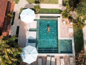 an overhead view of a man swimming in a pool with umbrellas at Terra Cottages Uluwatu Bali in Uluwatu