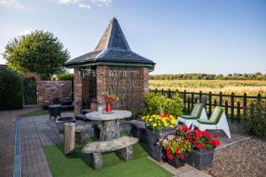 a gazebo with a table and chairs and flowers at Lincoln Holiday Retreat Cottage with Private Hot Tub in Lincoln