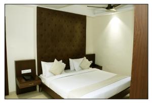 印多爾的住宿－Hotel Vrindavan Palace，卧室配有白色的床和木制床头板