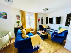 a living room with two blue couches and a tv at Captains Rest - 2 bedroom apartment in the heart of Brixham in Brixham