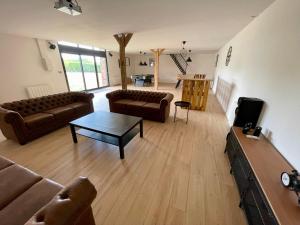 a living room with couches and a coffee table at Villa festive HOMAZING piscine privée 1h de Paris in Chantecoq