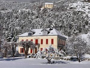 uma casa grande com portas vermelhas na neve em Magnifique appartement 8 couchages dans villa historique em Jausiers