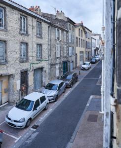 a city street with parked cars and buildings at La Cabane en Ville in Riom