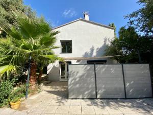 a white house with a gate and a palm tree at L'EFFERVESCENT in Saint-Péray