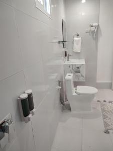 a white bathroom with a toilet and a sink at HARMAN SUITES Moalboal in Moalboal