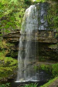 a waterfall on the side of a rock wall at Pentre Cottage near Craig y Nos in Pen-y-cae