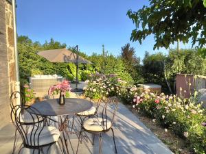 um pátio com uma mesa, cadeiras e flores em Gîte de charme 5 étoiles pour couple avec sauna et jacuzzi extérieurs privatifs em Peaugres