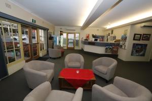 a waiting room with white chairs and a red table at Townhouse Motel Cowra in Cowra