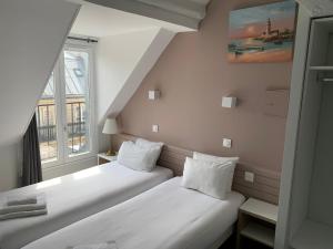 2 camas en una habitación pequeña con ventana en Hôtel Apollo Opéra, en París