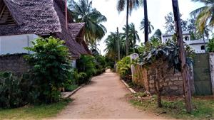 a dirt road next to a house with palm trees at V-Szameitat Homes, Kongo River in Diani Beach