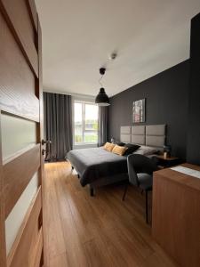 Schlafzimmer mit einem Bett, einem Schreibtisch und einem Fenster in der Unterkunft Apartamenty BRUNO i BIANCA w Symphony Modern Tower Gdynia 2 i 3 piętro in Gdynia