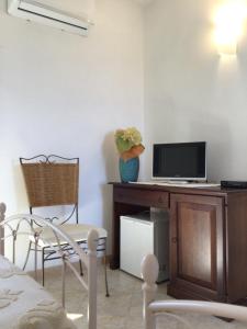 a room with a desk with a television and chairs at Agriturismo Lu Stabbiacciu in Aglientu