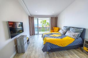 a bedroom with a bed with a yellow blanket and a television at Vista Oceano III in Caniço