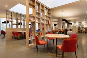 a restaurant with red chairs and a table and shelves at Ramada by Wyndham Amsterdam Airport Schiphol in Badhoevedorp