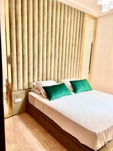 ein Bett mit zwei grünen Kissen in einem Zimmer in der Unterkunft Sublime appartement dans résidence prestigieuse in Marrakesch