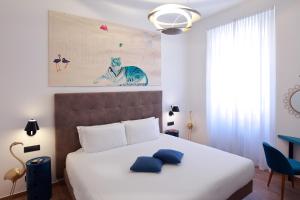 ein Schlafzimmer mit einem großen Bett mit blauen Kissen darauf in der Unterkunft Hotel Sanpi Milano in Mailand