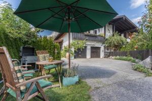 a patio with a table and a green umbrella at Zwischen Chiemsee und Bergen Dg in Bernau am Chiemsee