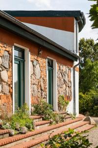 a brick house with green windows and stairs at Naturnahes, neu eingerichtetes Apartment mit 1 Schlafzimmer in Neu Gaarz