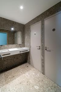 uma casa de banho com um chuveiro, um lavatório e uma porta em Adveniat Paris em Paris
