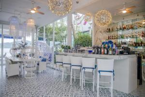 Royal Thai Villa Phuket - SHA Extra Plus في شاطئ راوايْ: بار وكراسي بيضاء وطاولة مع مشروبات