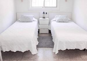 サン・バルトロメにあるSirenas on the beach IIの白いシーツと窓が備わるベッドルームのベッド2台