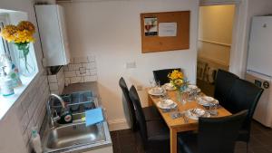 une table à manger dans une cuisine avec évier dans l'établissement Gillings Villa -5 Bed Great For Long & Short Stay!!! Gillingham Kent, à Hoo