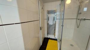 uma casa de banho com um chuveiro e um tapete amarelo em Gillings Villa -5 Bed Great For Long & Short Stay!!! Gillingham Kent em Hoo