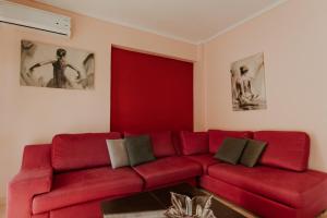 a red couch in a living room with two pictures at MARIAM APARTMENT in Thessaloniki