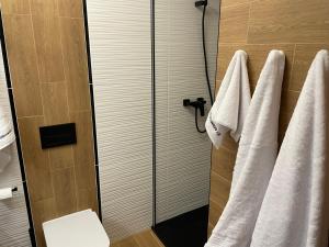 une salle de bain avec des serviettes blanches suspendues à une douche dans l'établissement Apartament Kasprowicza, à Kołobrzeg 20 autres photos