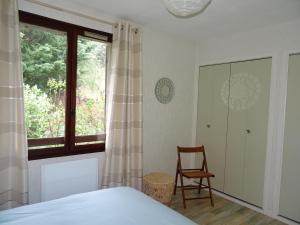 ein Schlafzimmer mit einem Bett, einem Stuhl und einem Fenster in der Unterkunft EMBRUN Superbe appartement classé 3 étoiles tout équipé avec vue sur montagnes in Saint-Sauveur