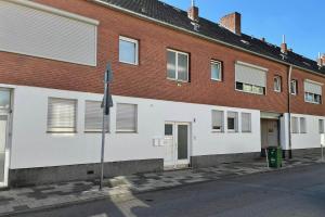 un bâtiment en briques avec des murs blancs et une rue dans l'établissement Equipped Apartment in Düren, à Düren