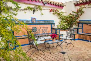 un patio con sillas, un banco y flores en CASA17 Santacruz Suites, en Sevilla