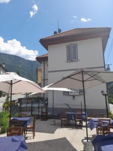 a patio with tables and umbrellas in front of a building at CA' DEL VINO Rooms- Varzo in Varzo