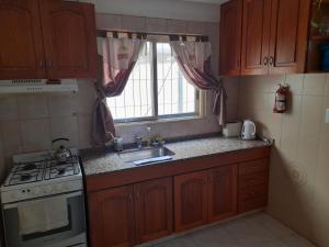 a kitchen with a sink and a stove and a window at Sueños del Golfo in Puerto Madryn