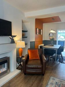 a living room with a leather chair and a fireplace at Lobster Cottage - Stylish 3 Bedroom Cottage in heart of Tenby Town, Pembrokeshire in Pembrokeshire