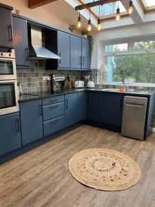 a kitchen with blue cabinets and a wooden floor at Lobster Cottage - Stylish 3 Bedroom Cottage in heart of Tenby Town, Pembrokeshire in Pembrokeshire