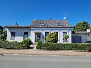 una casa blanca con arbustos frente a una calle en Ferienhaus Meerzeit, en Gelting