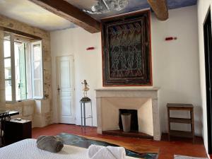 a living room with a fireplace and a painting on the wall at Le Regardeur in Saint-Rémy-de-Provence