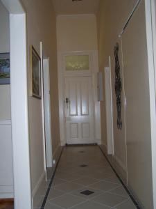 a hallway with a white door and a tiled floor at RJ's Bed & Breakfast in Maryborough