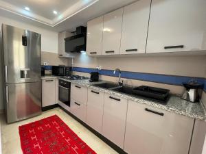 a kitchen with white cabinets and a red rug at Bright Flat Lac 2 Tunis in Tunis